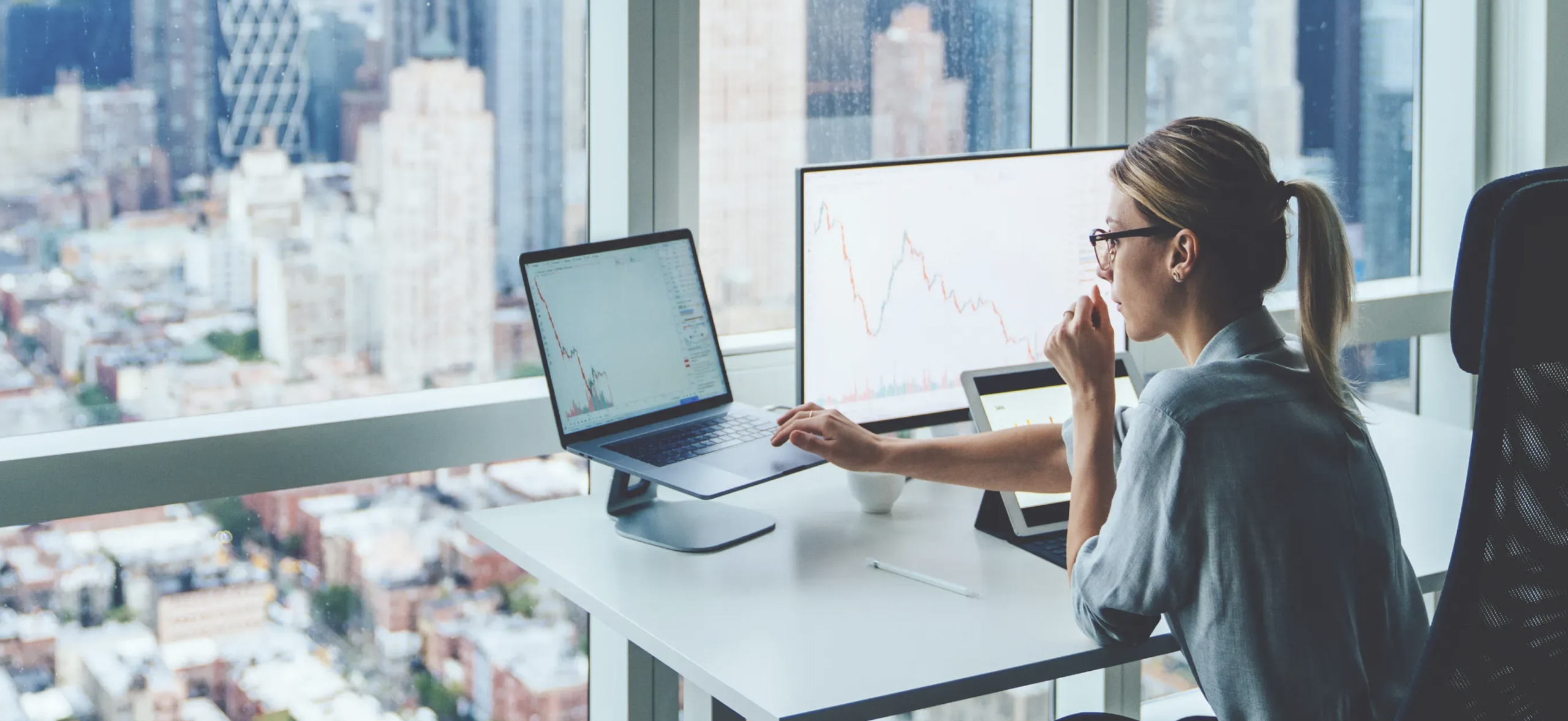 Imagem ilustrativa: Mulher em um escritório de vista panorâmica usando uma das melhores corretoras para investir no exterior